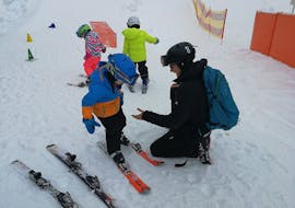 Child getting into the skis during the private lessons or kids with Wolfgang