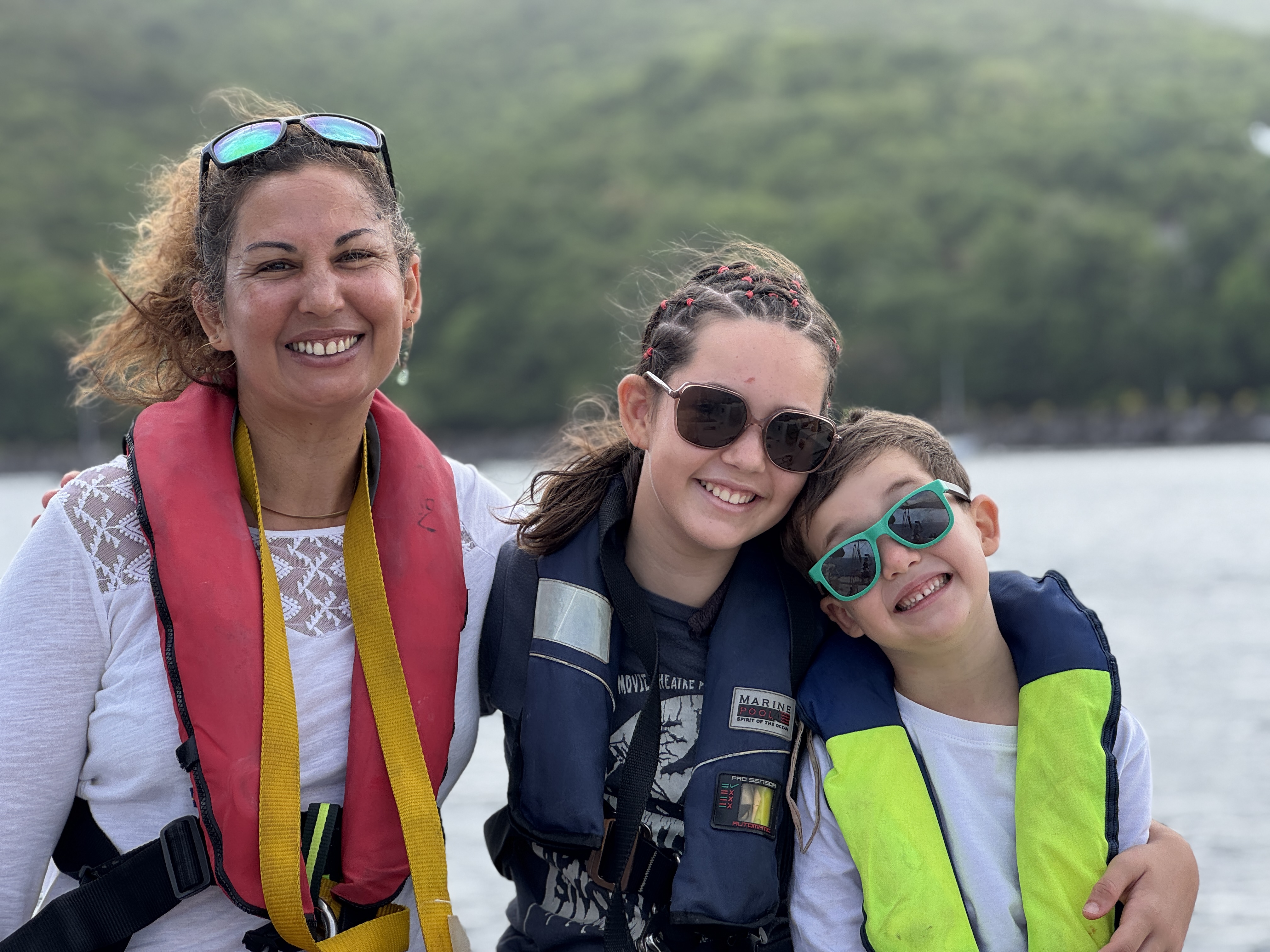 Eine lächelnde Mutter und zwei Kinder in Schwimmwesten genießen einen Segelbootausflug nach Les Saintes mit Schnorcheln und Mittagessen von Reve de Nav' Croisière.