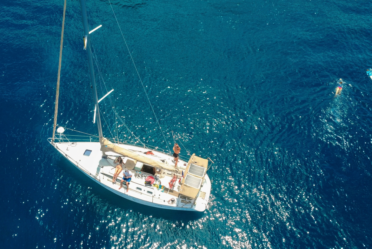 Zeiltocht en snorkelen met Reve de Nav' Croisière Gasten ontspannen op het dek terwijl anderen zwemmen in de sprankelende blauwe zee tijdens een zeiltocht naar Les Saintes met snorkelen en lunch, verzorgd door Reve de Nav' Croisière.