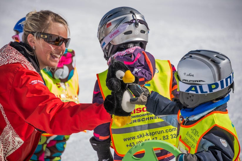 Een leraar speelt met een klein kind tijdens hun skilessen voor kinderen "BOBOs Baby-Club" (0-2 j.) bij Ski Dome Oberschneider Kaprun.