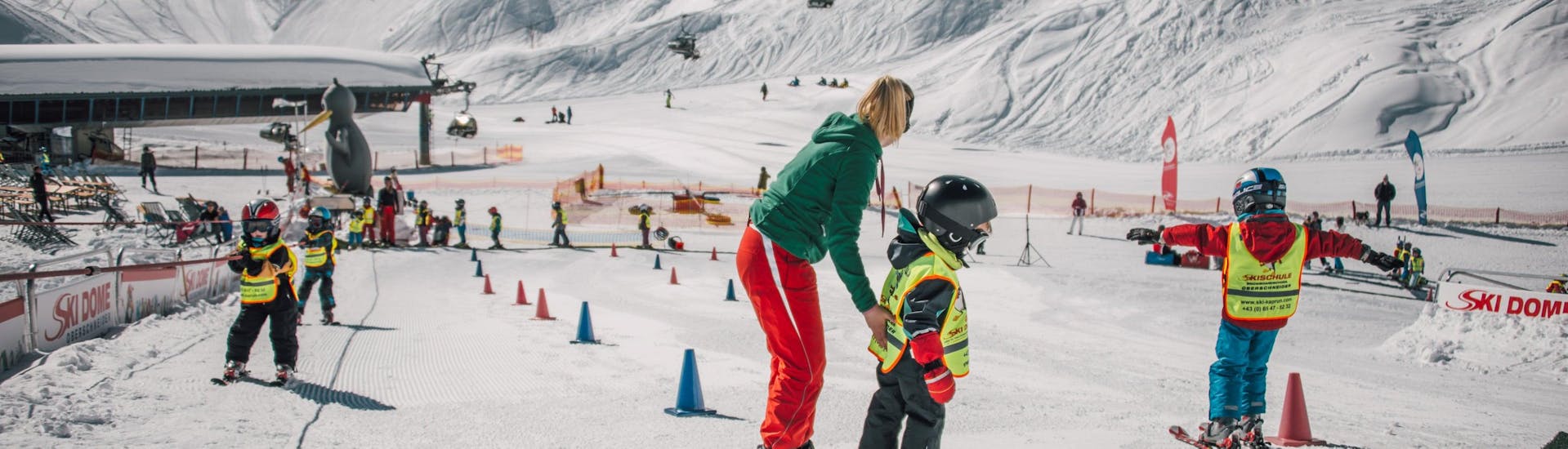 Een skileraar helpt kinderen tijdens de skilessen voor kinderen "BOBOs Bambini-Club" (3 jr.) voor beginners in Kaprum met Ski Dome Oberschneider.