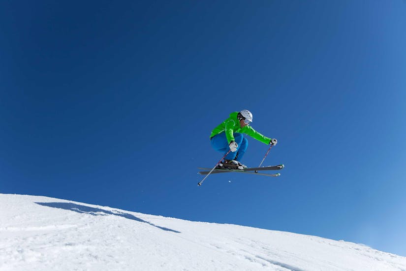 Een gevorderde skiër springt door de lucht met behulp van privé-skilessen voor volwassenen van alle niveaus in Kaprun.