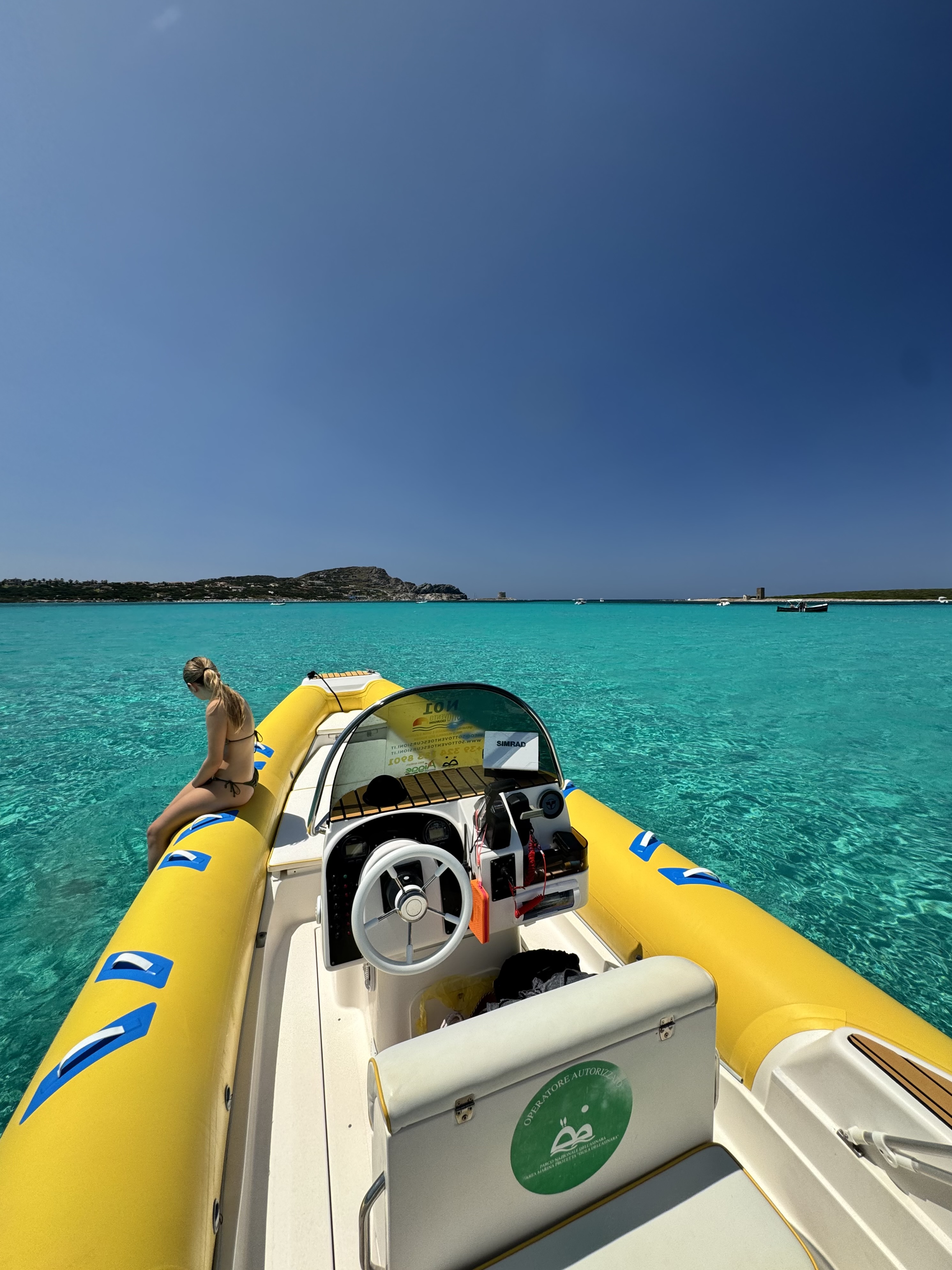 Eine Frau entspannt sich auf einem gelben Schlauchboot, das im kristallklaren türkisfarbenen Wasser vor Anker liegt, während einer privaten Tour durch den Nationalpark Asinara und La Pelosa ab Stintino mit Sottovento Escursioni Asinara.