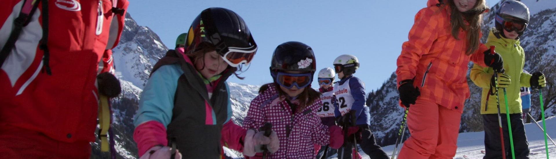 Een groep kinderen en hun instructeurs tijdens de Kids Skilessen (5-12 j.) voor beginners bij skischool Mittelberg. 