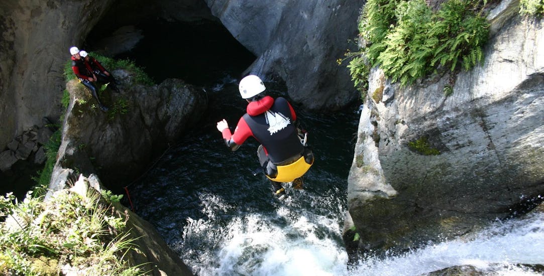 Eine abenteuerlustige Frau springt bei der Tour Canyoning in der Alpenrosenklamm im Ötztal für Einsteiger mit CanKick Ötztal von einem Wasserfall in ein natürliches Wasserbecken.