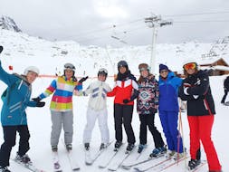 Eine Gruppe Erwachsener posiert vor einer der Pisten des Skigebiets 3 Vallées. Vormittags-Skikurs für Jugendliche und Erwachsene mit Ski Cool Val Thorens.