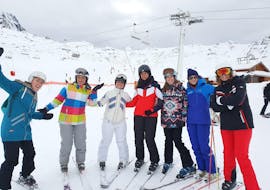 Eine Gruppe Erwachsener posiert vor einer der Pisten des Skigebiets 3 Vallées. Vormittags-Skikurs für Jugendliche und Erwachsene mit Ski Cool Val Thorens.