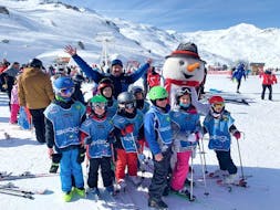 Kids are taking a group picture with their ski instructor from the ski school Ski Cool Val Thorens after their Kids Ski Lessons (5-12 y.) - Morning.