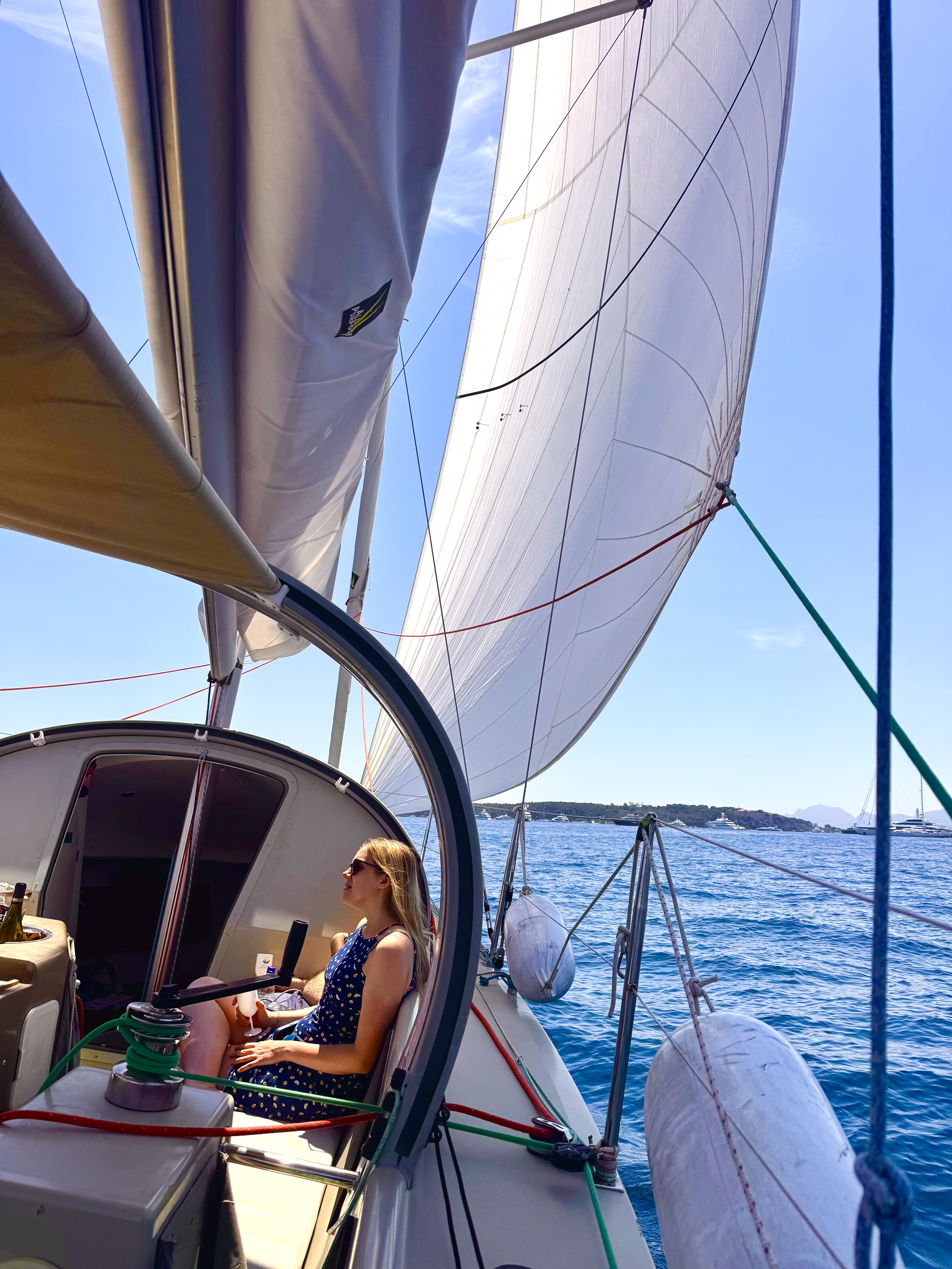 Femme se détendant à la barre d'un voilier à Antibes Une femme se détend avec un verre de vin sur un voilier lors d'une excursion en mer à Antibes avec Cap Sail Aventures Antibes.