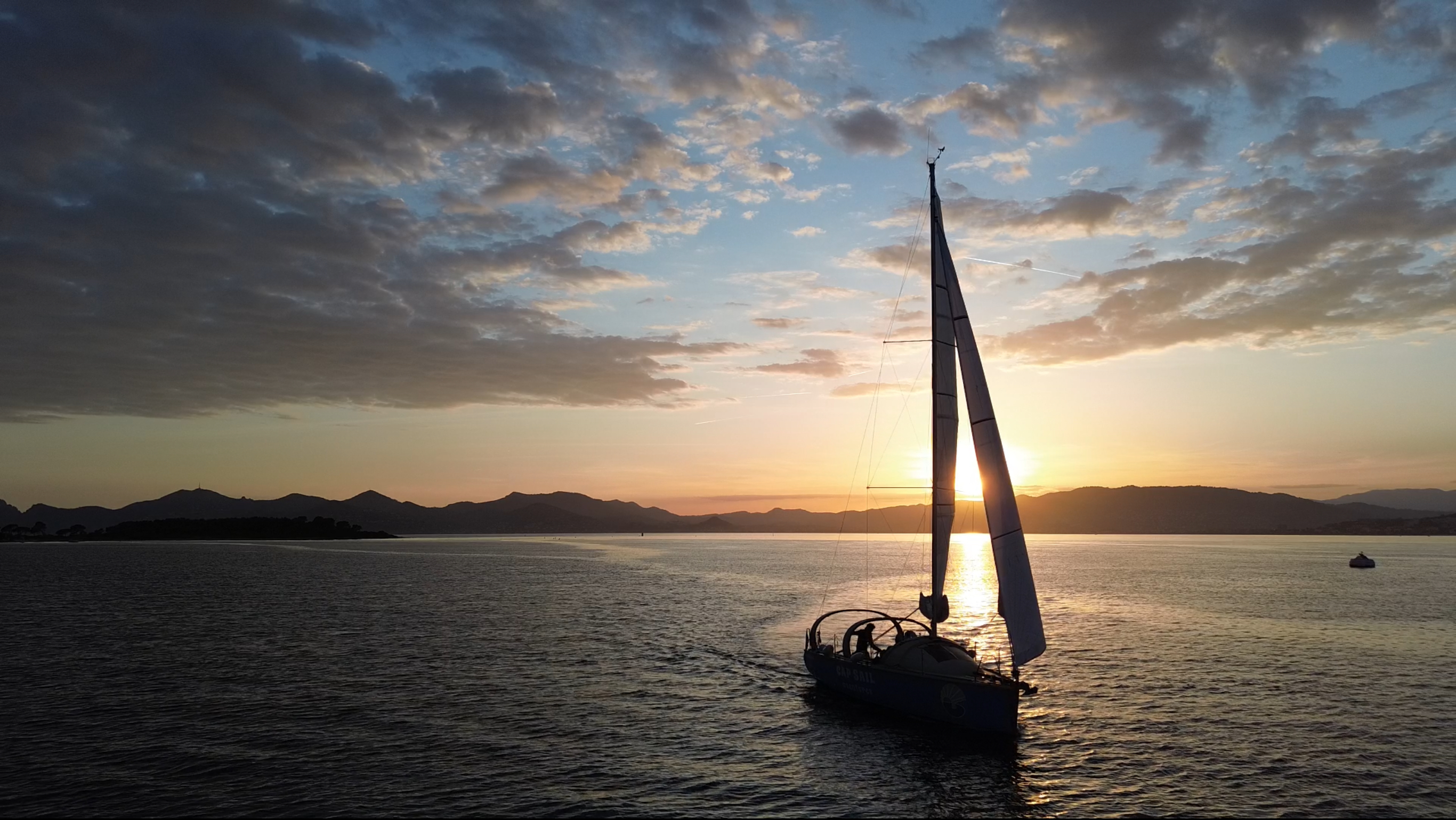 Gita in barca a vela al tramonto al largo della costa di Antibes Una barca a vela della Cap Sail Aventures Antibes solca le acque al tramonto, durante un aperitivo al largo della costa di Antibes o delle isole di Lérins.