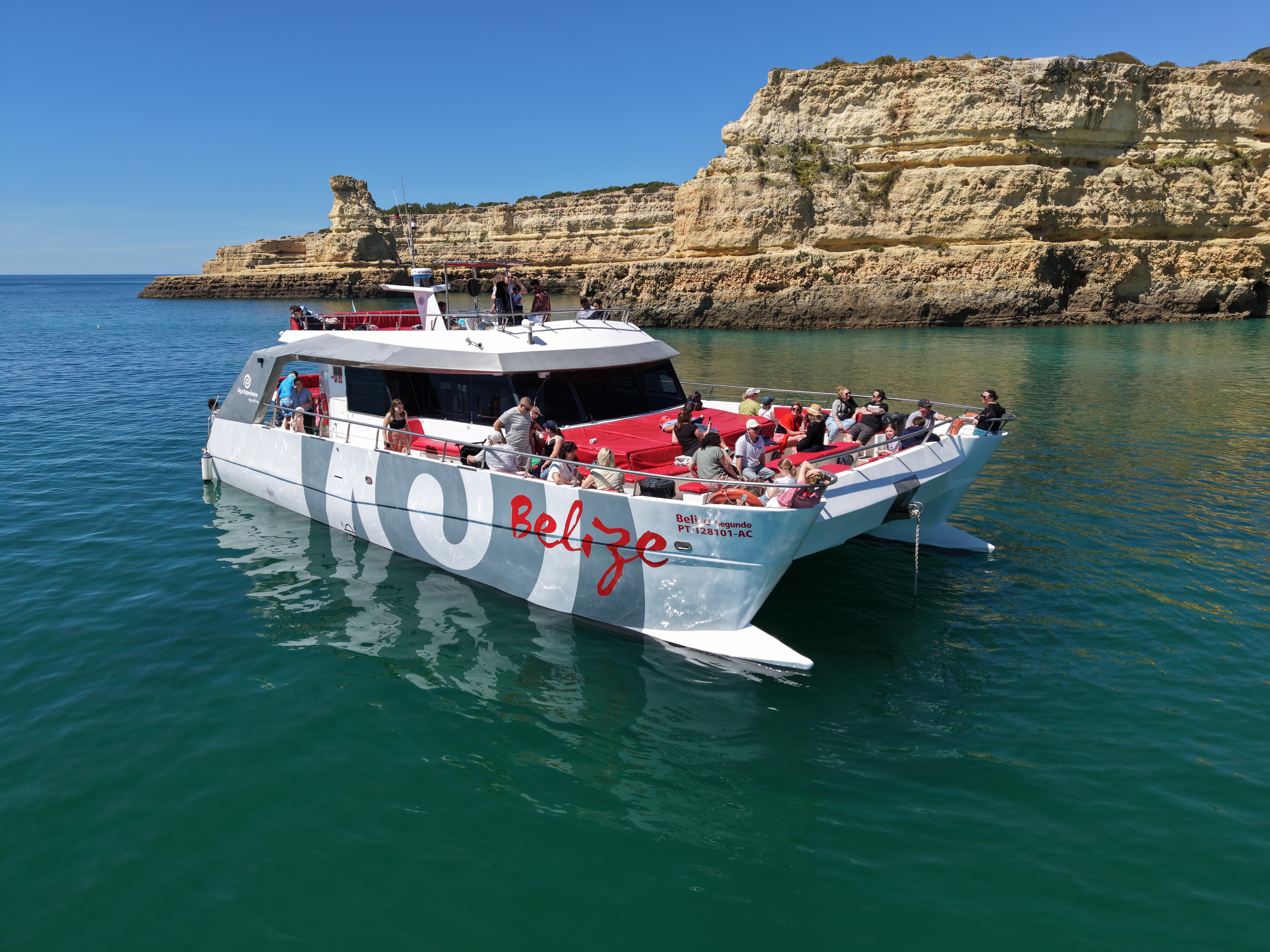 The AlgarExperience catamaran with tourists aboard cruises along the Algarve coast during a boat trip to the Benagil Caves & coastline from Vilamoura.