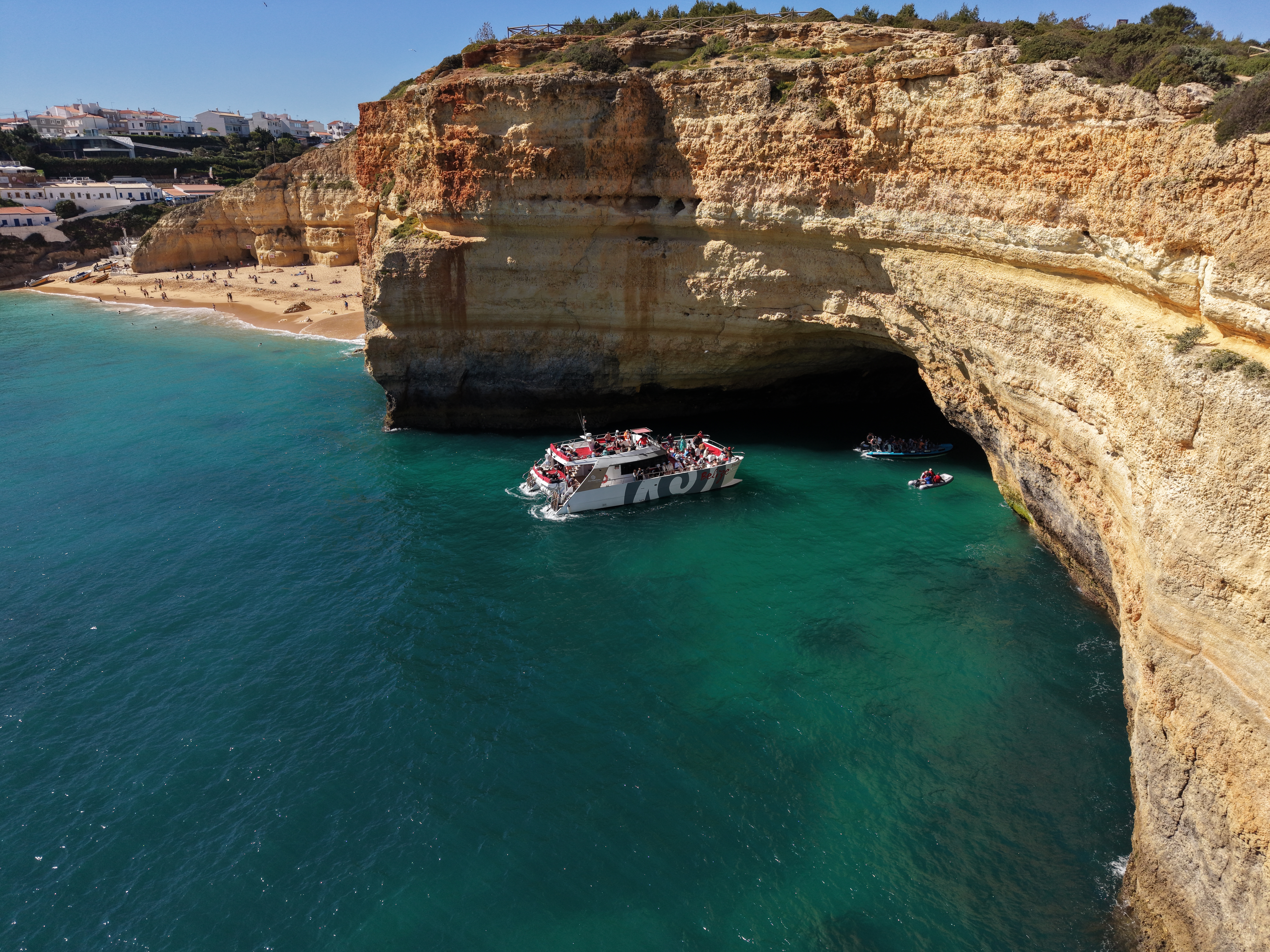 El catamarán AlgarExperience navega por las aguas turquesas junto a las cuevas de Benagil durante la excursión en catamarán "Albufeira - Cuevas de Benagil y costa".