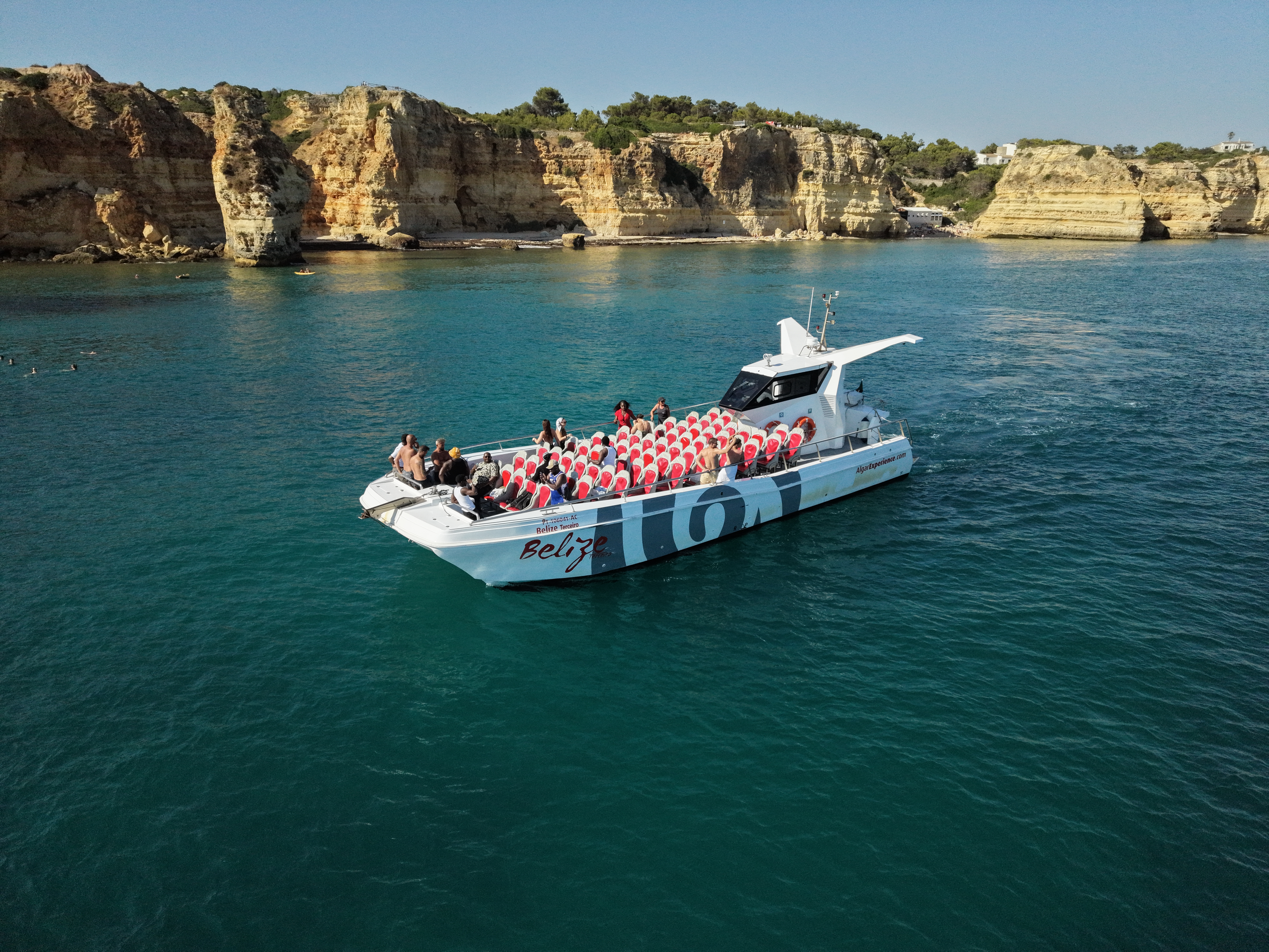 Un catamaran AlgarExperience avec des passagers à bord de croisières le long des falaises dorées de la côte de l'Algarve lors d'une excursion en catamaran à Portimão : Dauphins et grottes de Benagil.
