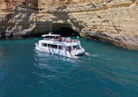Algar Experience: crociera alle famose grotte di Benagil Una barca turistica bianca di AlgarExperience naviga con i passeggeri lungo le splendide scogliere e le grotte marine durante una crociera a Portimão: Grotte di Benagil con brunch e open bar.
