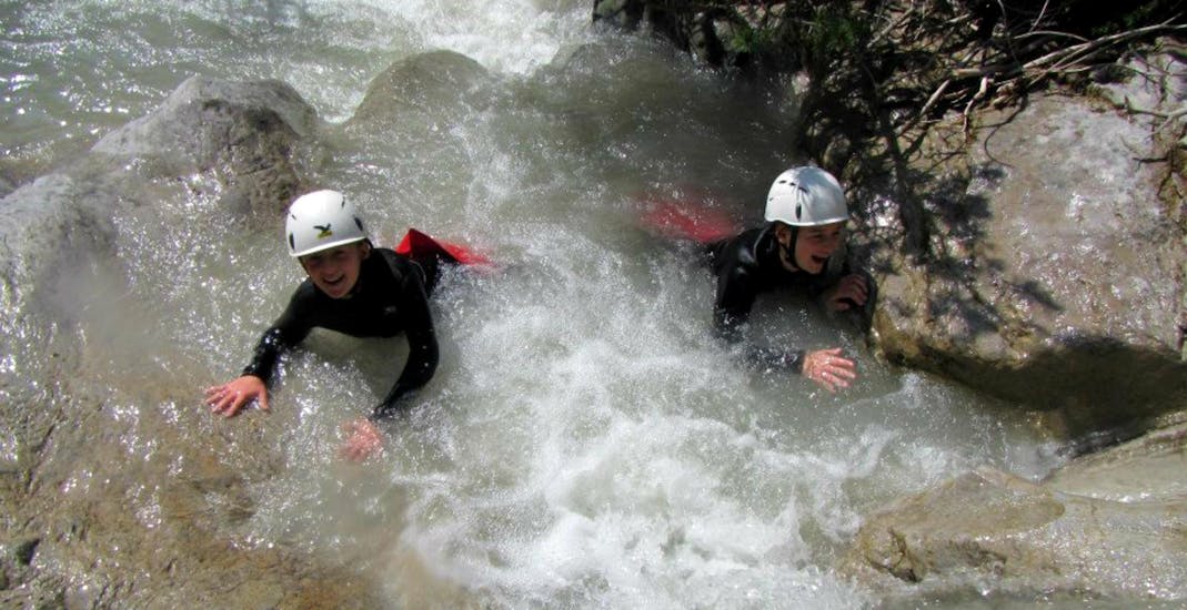 Two children splash around in a natural pool during their canyoning tour for children and families in the Rosengartenschlucht with the experienced instructors from Natur Pur Outdoorsports.