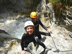 A little girl having fun climbing up a canyon on her Canyoning Tour for Kids and Families at Rosengartenschlucht under the guidance of an experienced instructor from Natur Pur Outdoorsports.