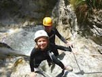 Ein kleines Mädchen, das auf ihrer Canyoning Tour für Kinder und Familien in der Rosengartenschlucht unter der Leitung eines erfahrenen Lehrers von Natur Pur Outdoorsports Spaß beim Erklimmen eines Canyons hat.