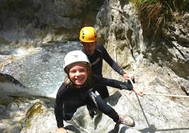 Ein kleines Mädchen, das auf ihrer Canyoning Tour für Kinder und Familien in der Rosengartenschlucht unter der Leitung eines erfahrenen Lehrers von Natur Pur Outdoorsports Spaß beim Erklimmen eines Canyons hat.