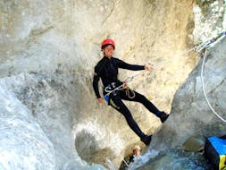 Eine Frau, die auf ihrer Canyoning Anfängertour im Einsteigercanyon unter der Aufsicht der erfahrenen Lehrer von Natur Pur Outdoorsports Spaß beim Abseilen von einer Klippe hat.