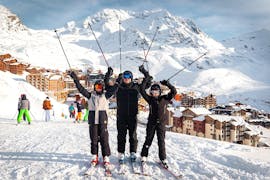 Due bambini e un istruttore della scuola di sci Ski Cool Val Thorens posano davanti alla stazione sciistica al termine delle lezioni private di sci per bambini e ragazzi.