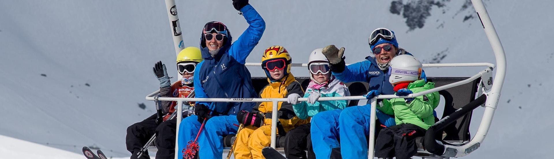 Un gruppo di bambini sale sulla seggiovia insieme ai loro maestri di sci della scuola Ski Cool durante le lezioni private di sci per bambini - vacanze scolastiche - tutte le età nella stazione sciistica di Val Thorens.