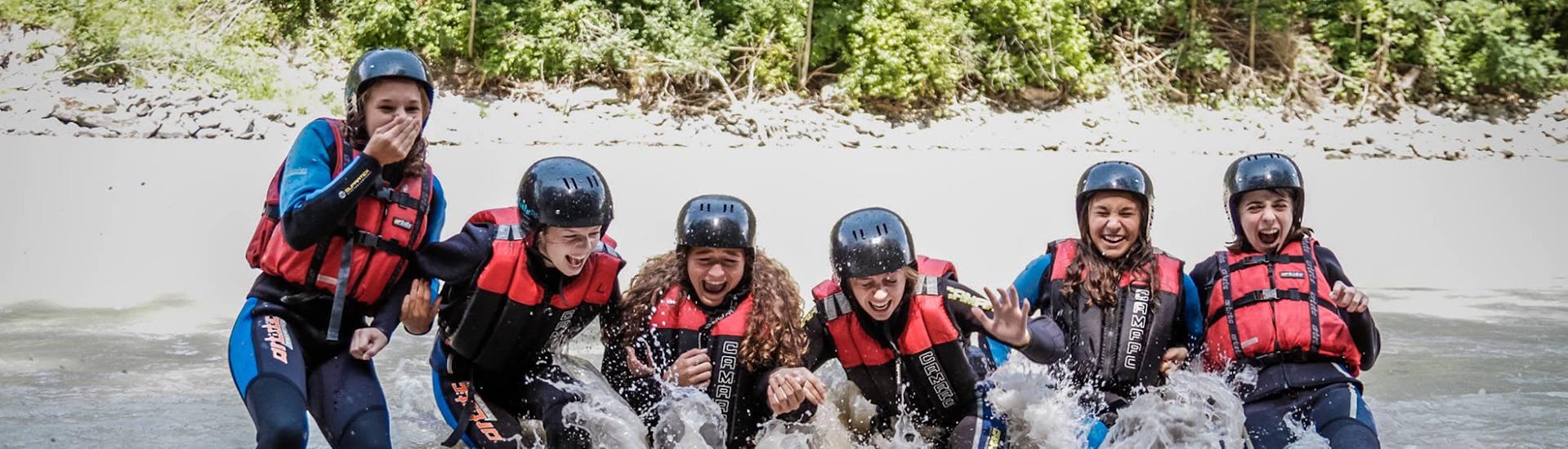 Een groep deelnemers valt in het water tijdens het raften op de Inn River - Perfecte start met H2O Adventure Ried.