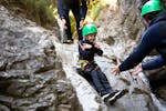 Ein Kind rutscht eine natürliche Rutsche beim Canyoning für Familien bei Ried im Oberinntal mit H2O Adventure Ried hinunter.