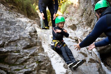 Een kind glijdt van een natuurlijke glijbaan tijdens canyoning voor gezinnen in de buurt van Ried im Oberinntal met H2O Adventure Ried.