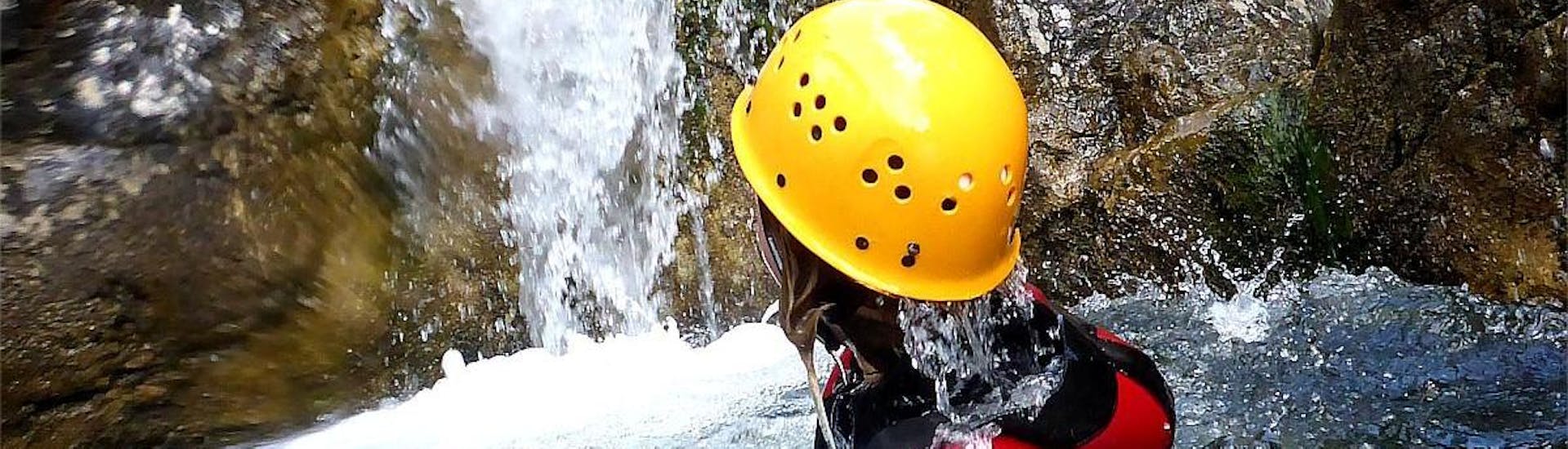 A costumer in the water next to a waterfall during the Advanced Canyoning in Allgäu - Day Tour with Die Canyonauten Allgäu