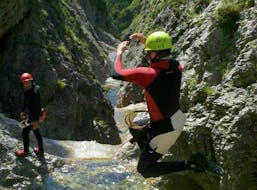During the Canyoning for Beginners at Lake Sylvenstein, a participant is jumping into a natural pool under the watchful eye of a certified canyoning instructor from Montevia.