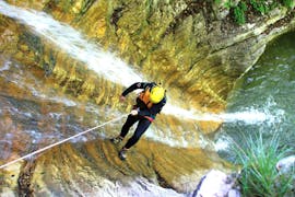 Ein Teilnehmer des Extreme Canyoning am Sylvensteinsee mit Montevia seilt sich über einen Wasserfall in der Schlucht ab.