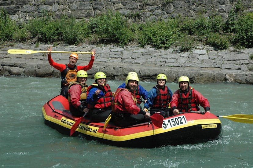 Group of friends sitting in the boat with the guide and looking forward to the rafting tour on the Salzach near Zell am See with Adventure Service Outdoorsports.