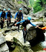 A group of friends is having fun climbing down a small waterfall on their Canyoning Tour "Jump & Splash" in the beautiful gorge Almbach together with the experienced guides of Frost Rafting & Canyoning Tours.