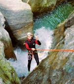 A participant of the Canyoning "Blue Lagoon" in Zemmschlucht is roping down over a high rock cliff with the help of an experienced guide from Freiluftakademie.