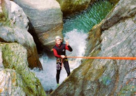 A participant of the Canyoning "Blue Lagoon" in Zemmschlucht is roping down over a high rock cliff with the help of an experienced guide from Freiluftakademie.
