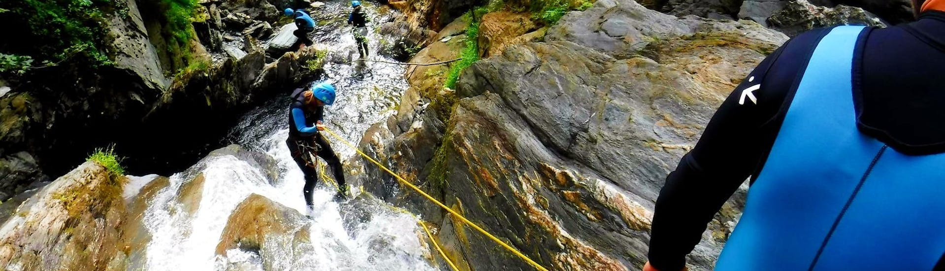 Eine Teilnehmerin seilt sich beim Canyoning im Rettenbach - Online mit FROST einen Wasserfall hinunter.