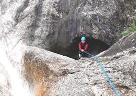 Beim Canyoning für Mutige - Vertical Valley seilt sich eine Frau unter der Aufsicht eines erfahrenen Canyoningguides von Bergführer Salzburg eine Schlucht hinab.