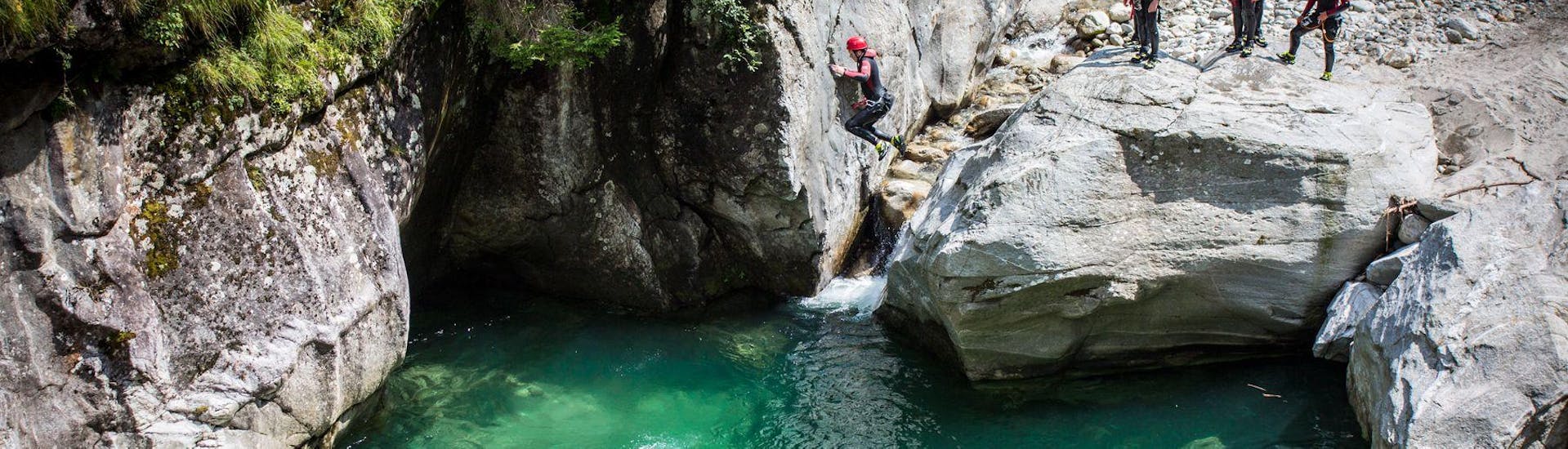 Die Teilnehmer der Tour Canyoning für Familien - Zemmschlucht von Mountain Sports Mayrhofen springen nach und nach in ein natürliches Becken.