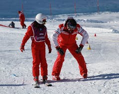 Ein Skilehrer der ESF Courchevel zeigt während eines privaten Skikurses für Kinder die richtige Haltung auf den Skiern.
