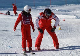 Un moniteur de l'ESF Courchevel montre pendant un cours particulier de ski pour enfants la bonne posture à avoir sur des skis.