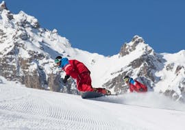 Los snowboarders siguen a su instructor en las pistas durante una lección privada de snowboard, con la ESF Courchevel.