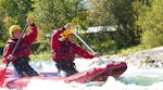 Zwei Teilnehmer des Rafting im Kanadier für Entdecker auf der Isar mit Montevia paddeln mit voller Kraft durch eine Stromschnelle auf dem Fluss.