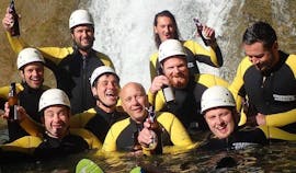 Eine Gruppe von Freunden posiert beim Canyoning für Junggesellen im Allgäu mit canyoning erleben für ein Foto vor einem Wasserfall.