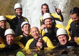 A group of friends is posing for a photo in front of a waterfall during the Canyoning Bachelor Party in the Allgäu with canyoning erleben.