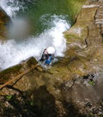 Tijdens Canyoning "Rocks & Ropes" voor sportieve beginners met Base Camp strijkt een deelnemer naar beneden over een waterval.