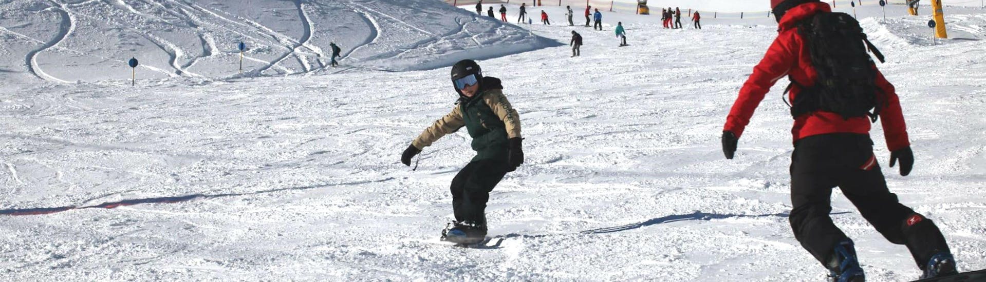 A young snowboarder is practicing his front and backside turns during his Snowboarding Lessons for Kids "All-Inclusive" (9-15 years) with the ski school Ski- und Snowboardschule Vacancia.