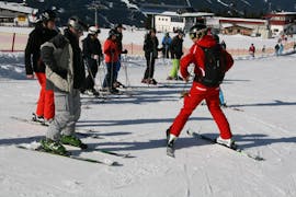 A ski instructor from the ski school Skischule Lechner in Zell am Ziller is showing a group of adults how to ski during their Ski Lessons for Adults - Beginners.