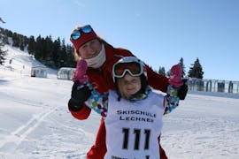 Een jong meisje en haar skileraar van de skischool Skischule Lechner glimlachen naar de camera tijdens de skilessen voor kinderen voor beginners (5-14 jaar).