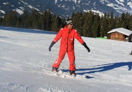 Ein Snowboardlehrer der Skischule Lechner in Zell am Ziller zeigt beim Snowboardkurs für Erwachsene - Anfänger wie man richtig die Piste hinunter fährt.