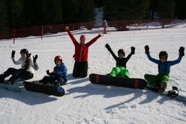 Eine Gruppe Kinder und deren Snowboardlehrerin der Skischule Lechner machen beim Snowboardkurs für Kinder (8-14 Jahre) - Anfänger eine kurze Pause im Schnee.
